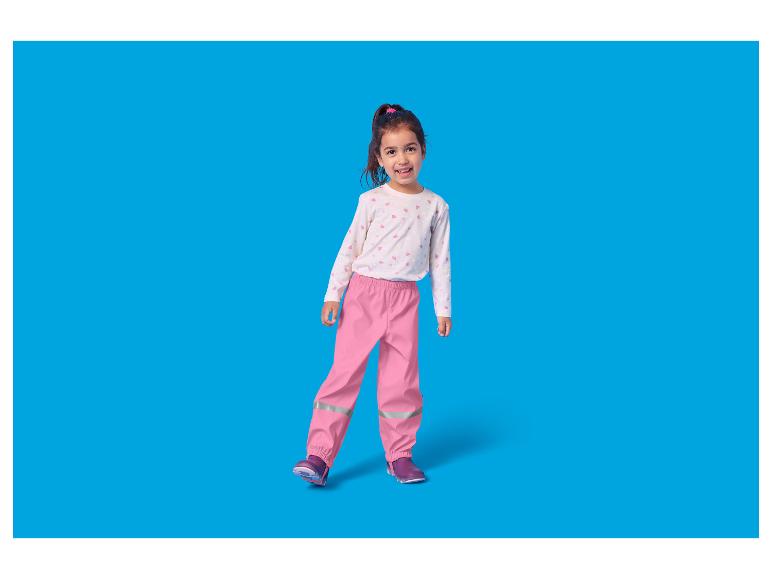 Meisje in roze waterdichte broek en shirt met hartjes.