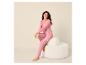 Vrouw in roze pyjama met stippen zit lachend op een witte kruk.
