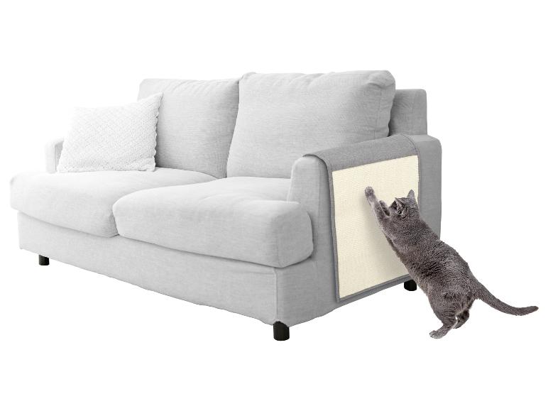 Grijze bank met een kat die aan een krabplank op de armleuning krabt.
