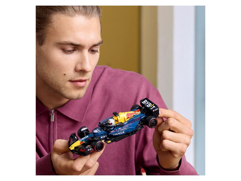 Een man houdt een Lego Red Bull Racing Formule 1 raceauto vast.