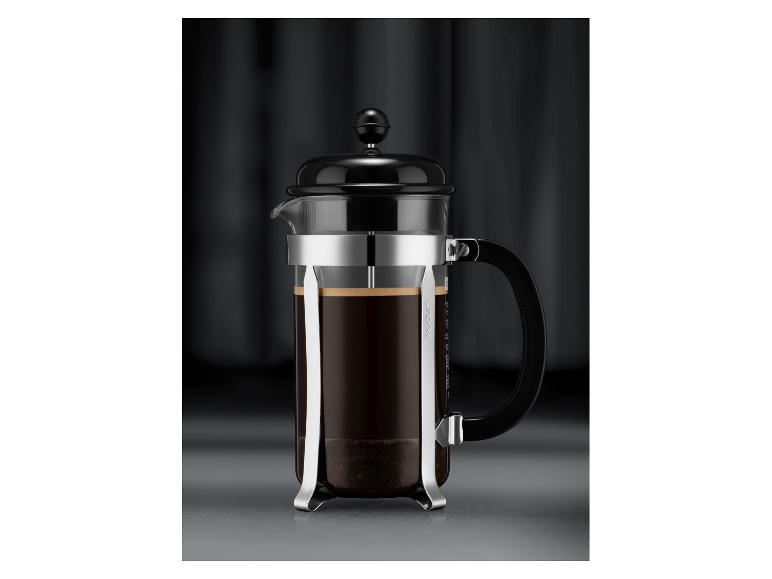 Zwarte koffiepers met glazen kan en metalen frame, gevuld met koffie.