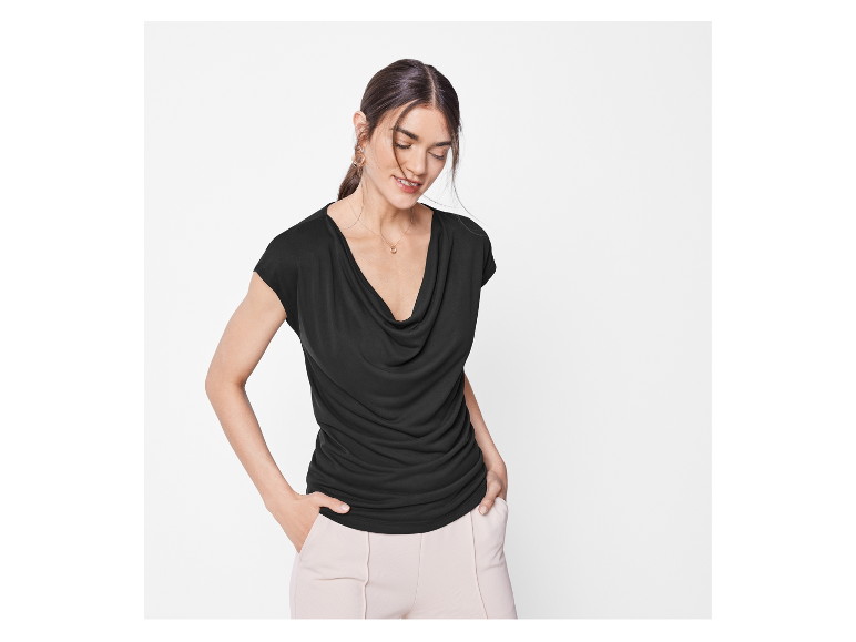 Een vrouw draagt een zwart gedrapeerd topje met korte mouwen.