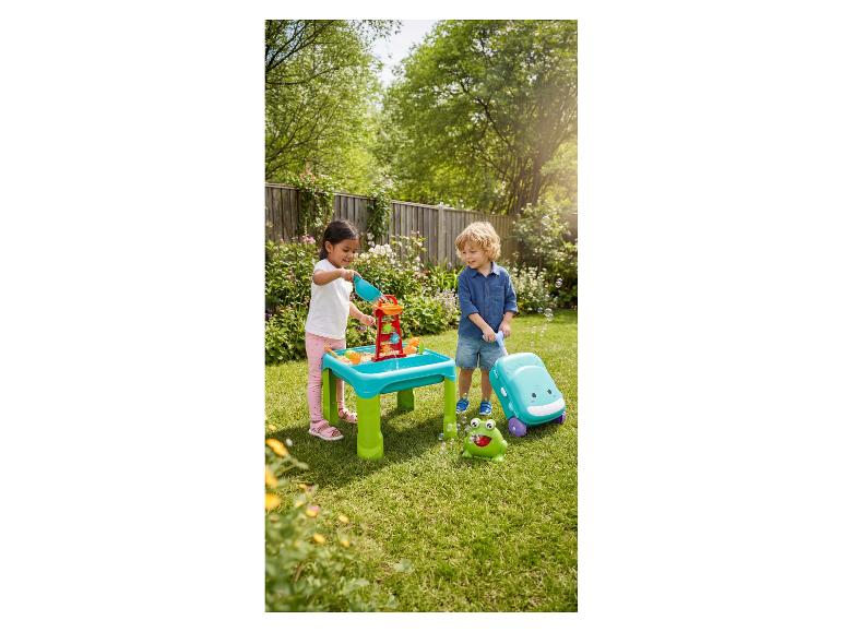 Kinderen spelen met watertafel en bellenblaasmachine in de tuin.