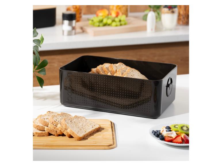Zwarte broodtrommel met gesneden brood en ontbijt op een aanrecht.