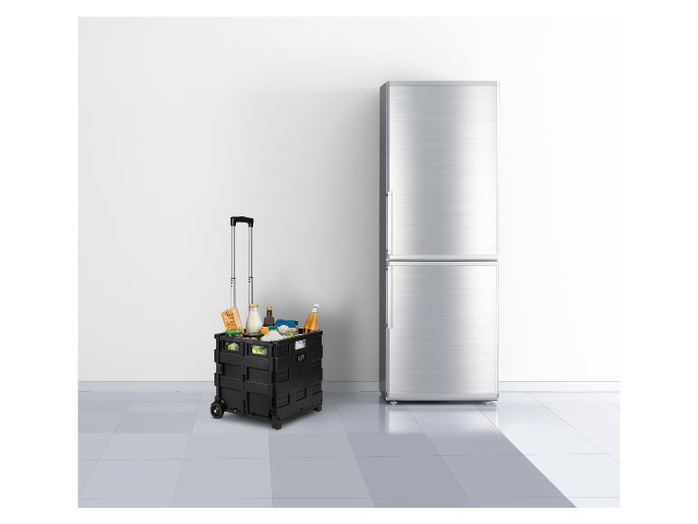 Zwarte opvouwbare boodschappenkar met boodschappen naast een zilveren koelkast.