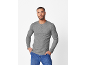 Man in grijs shirt met lange mouwen en blauwe jeans, met handen in zakken.