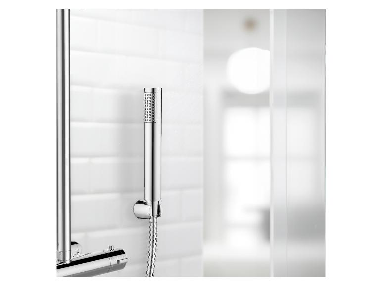 Een chromen doucheset met handdouche, gemonteerd op een witte betegelde muur.