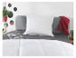 Slaapkamer met wit kussen, dekbed, grijs beddengoed en rood plaid.