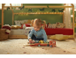 Klein kind speelt met houten speelgoedvrachtwagen met auto's in kinderkamer.