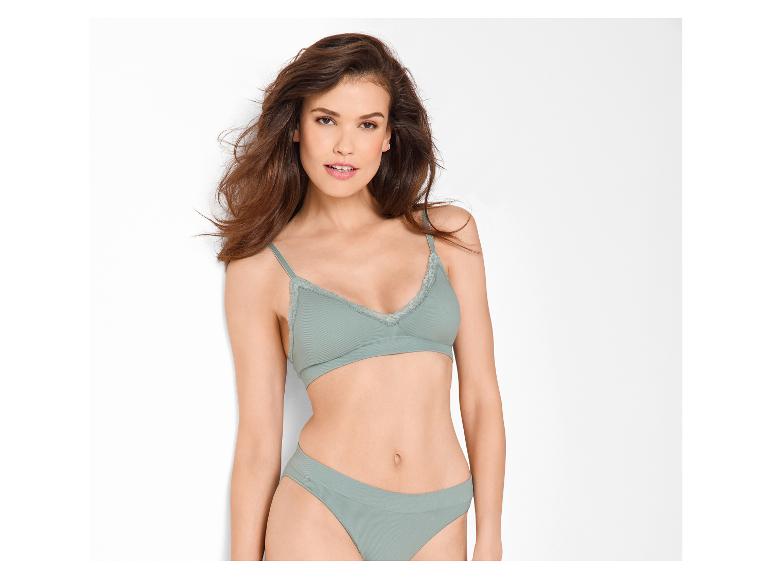 Vrouw in groene beha en slip, met los haar, lachend naar de camera.