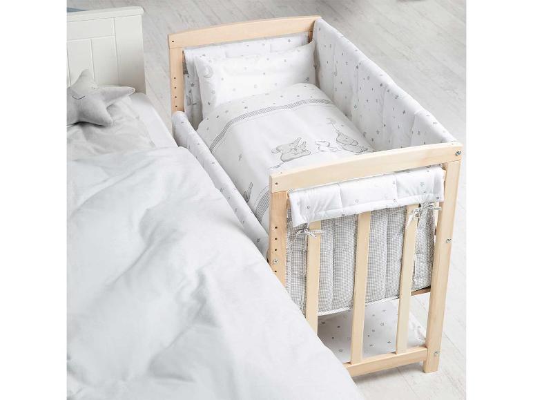 Een houten babybedje met sterrenprint en een grijze ster knuffel.