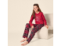 Meisje in rode pyjama met 'Let's have breakfast' opdruk en geruite broek, zittend op een stoel.