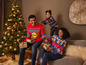 Een familie in kersttruien met Lidl logo's, met kerstcadeaus en een kerstboom.