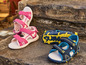 Twee paar kindersandalen, roze met hartjes en blauwe met gele accenten.