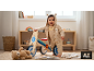 Lachende baby met berenmuts, vasthoudend aan een houten loopfiets.