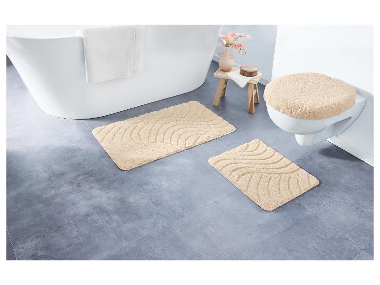 Beige badmatten met golvend patroon en een toiletbril met zachte bekleding.