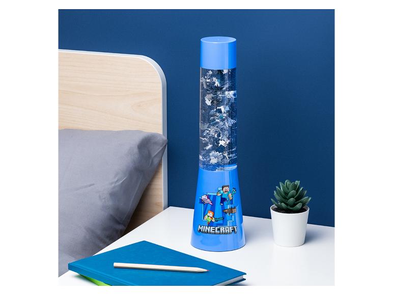 Blauwe lavalamp met videogame-thema, een notitieboekje en een potlood op een nachtkastje.