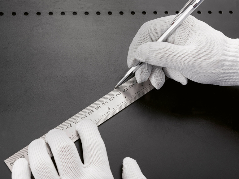 Een hand met een witte handschoen gebruikt een metalen liniaal en een pen om te meten.