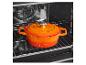 Oranje gietijzeren pan met deksel in een oven