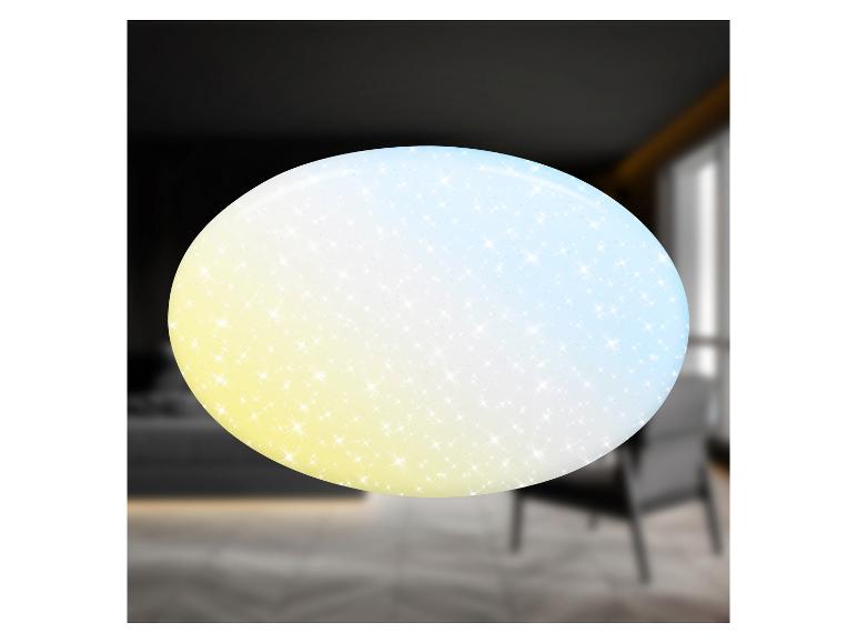 Ovale plafondlamp met een sprankelend kleurverloop van geel naar blauw, in een vage kamer.