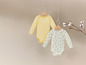 Twee baby-onesies, een gele en een met bijenprint.