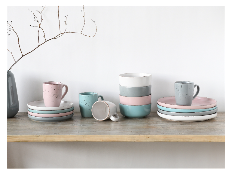 Gestackte mokken en kommen, pastelkleurige borden.