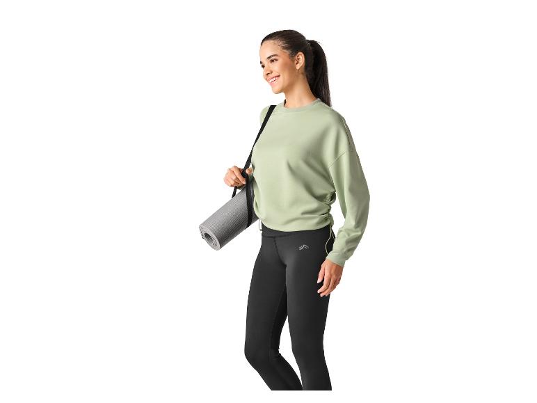 Vrouw in sportkleding met yogamat over haar schouder.