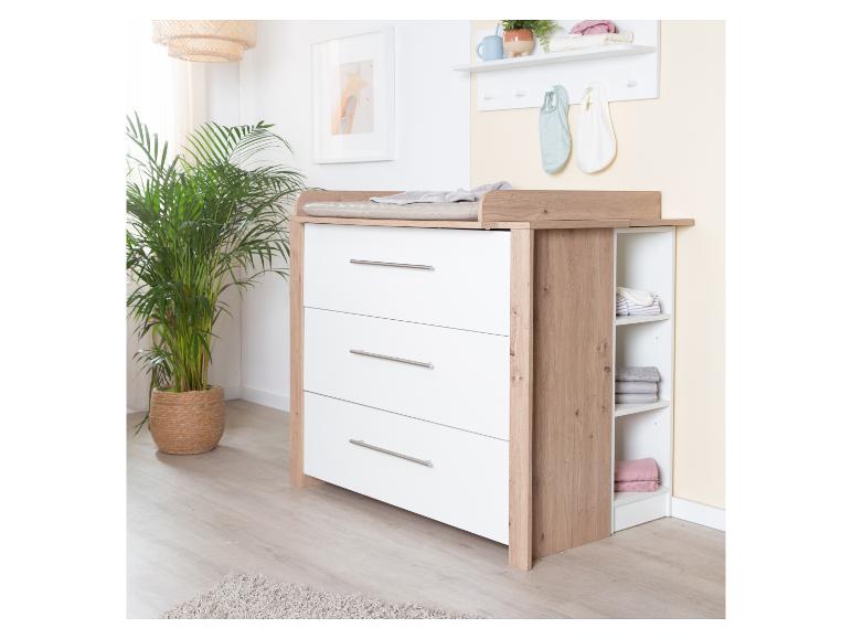 Houten commode met witte lades en open planken in een lichte kamer.