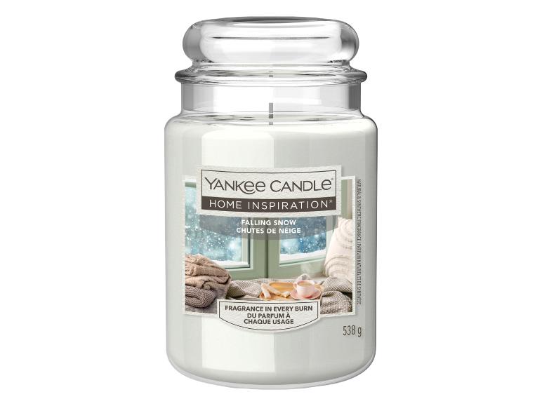 Witte kaars in een glazen pot met een etiket dat een besneeuwd raam toont, getiteld 'Falling Snow'.