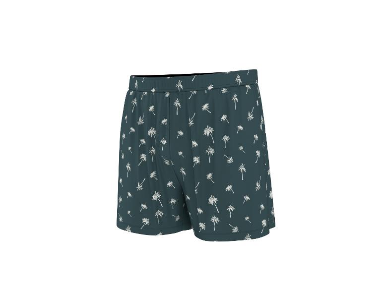 Donkergroene zwemshort met witte palmbomenprint.