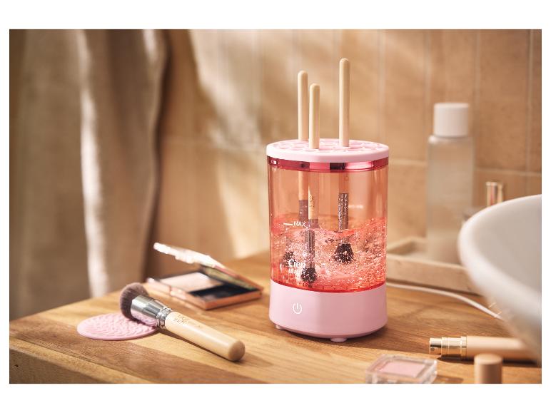 Roze make-upkwastenreiniger met kwasten erin, op een houten aanrecht.