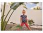 Meisje in aardbeien T-shirt en rode legging, staand in een tuin.