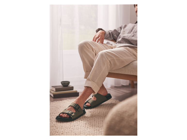 Een man draagt groene sandalen.