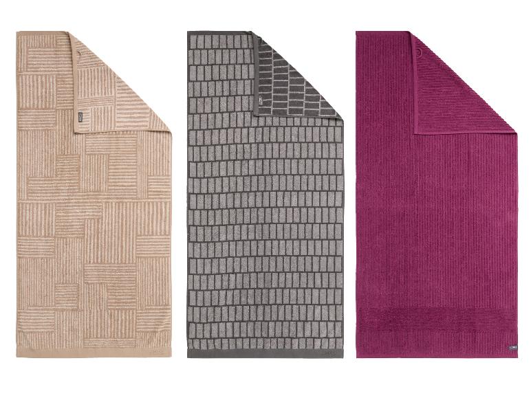Drie badhanddoeken: beige met geometrische patronen, grijs met baksteenpatroon en een effen paarse.