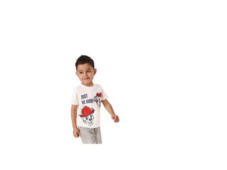 Jongen in een wit T-shirt met 'JUST BE KIND!'-opdruk en grijze broek.