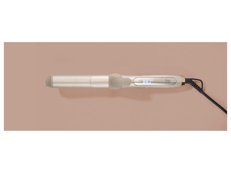 Gouden krultang met digitaal display en zwart snoer op een beige achtergrond.