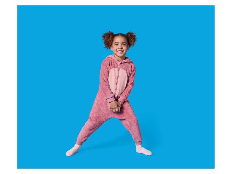 Een lachend meisje draagt een roze pluizige onesie.