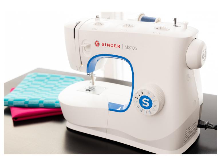 Witte naaimachine met blauwe accenten, een klos blauw garen en kleurrijke stoffen