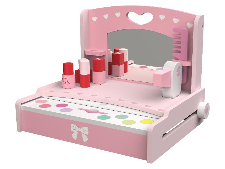 Roze kinderkaptafel met spiegel, cosmetica en accessoires.