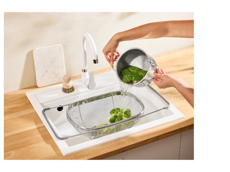 Persoon giet broccoli uit pan in vergiet in gootsteen.