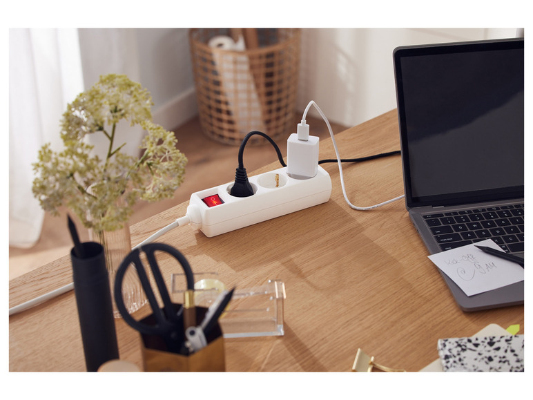 Een wit stopcontact met een laptop en een oplader.