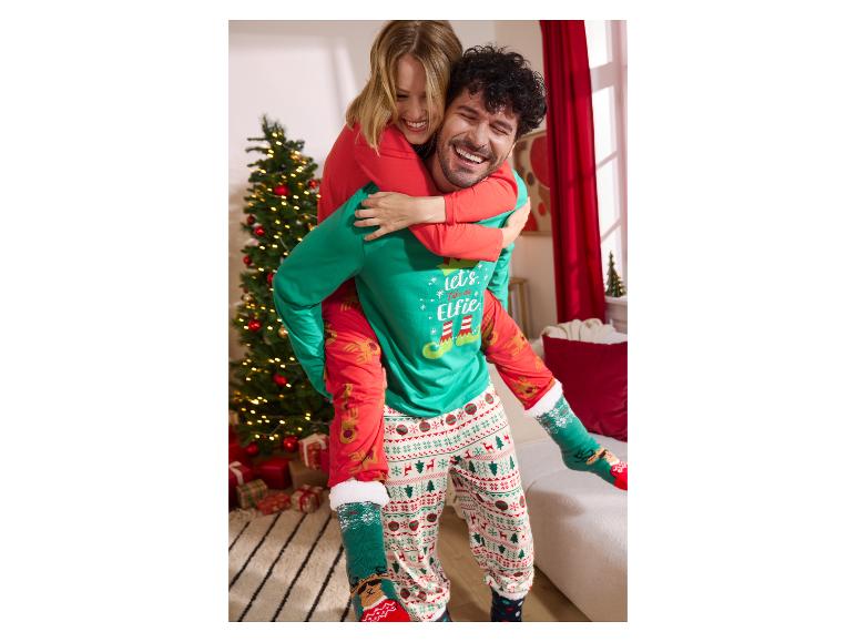 Paar in bijpassende kerstpyjama's, vrouw op de rug van de man, beiden lachend.