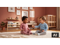 Twee baby's spelen op een vloerkleed in een kinderkamer met houten wieg en planken.