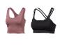 Twee sportbeha's, één roze-bruin en één zwart, op een witte achtergrond.