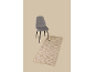 Grijze stoel met zwarte poten en een beige vloerkleed met geometrisch patroon.