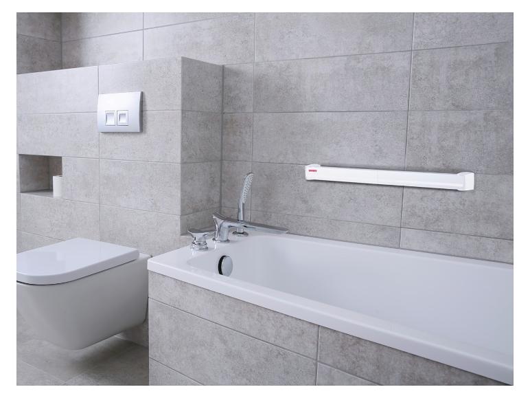 Badkamer met bad, toilet en wandgemonteerde handdoekdroger.