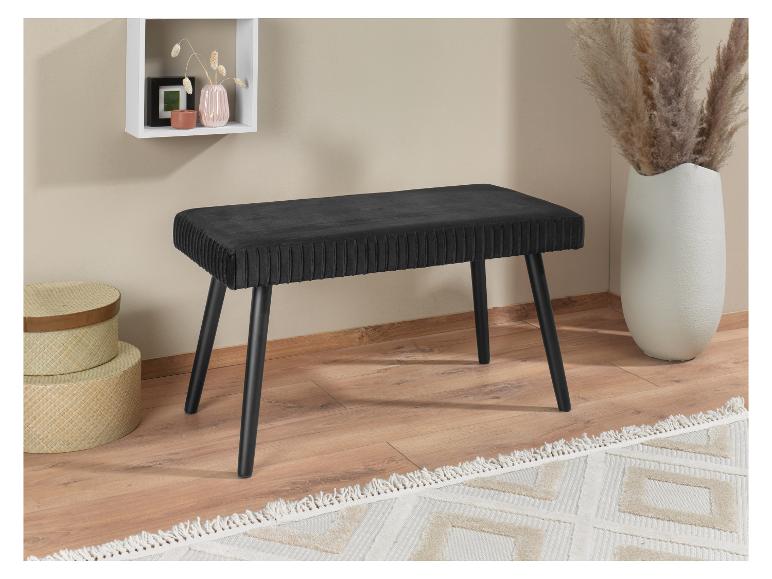 Een zwart fluwelen bankje op houten poten in een modern interieur.