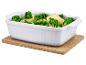 Witte keramische ovenschaal met broccoli en aardappelen op een kurkmat.