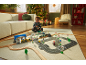 Kind speelt met houten treinset en wegenmat op een vloerkleed in een feestelijke woonkamer.