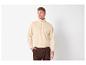 Man in beige sweatshirt met rits en bruine broek.